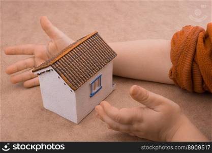Little model house and  a hand  on a light  brown color background
