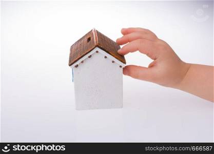 Little model house and a hand on a light white color background