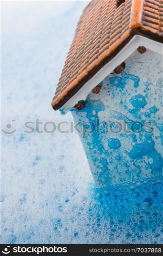 Little model house and a painting brush in foamy water