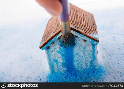 Little model house and a painting brush in foamy water