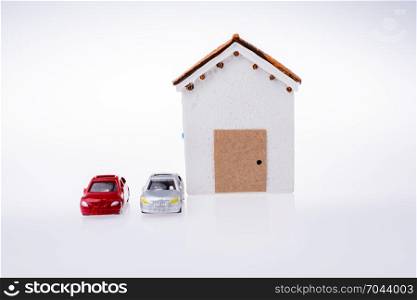 Little model house and two cars on a white background