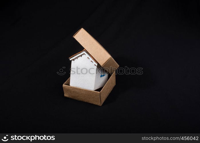 Little model house in hand in a paper box