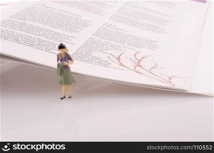 Little model woman figure standing by the side of the magazine pages