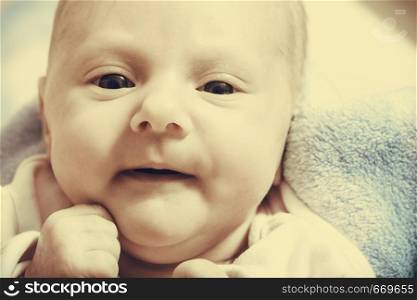 Little newborn baby in pyjamas lying on back. Face expression. Family, parenthood, childhood concept. Sepia.. Newborn baby lying in pyjamas and towel