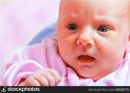 Little newborn baby in pyjamas lying on back. Surprised face expression. Family, parenthood, childhood concept.. Newborn baby lying in pyjamas and towel