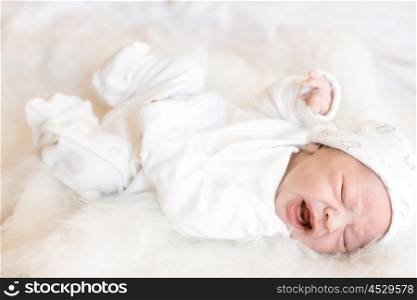 Little newborn baby over a white fur