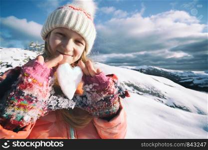 little Norwegian girl holds in her hands a heart of snow. Fun winter. Norway