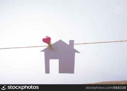 Little paper house attached to a string with a heart clip