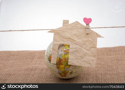 Little paper house attached to a string with a heart clip by a globe