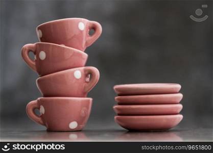 Little pink toy porcelain cups and plates with white dots on gray background