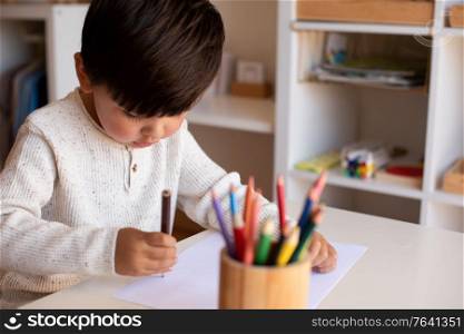 Little preschooler kid drawing with coloured pencils. Homeschooling. Learning community. Montessori school.