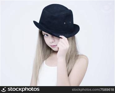 little pretty girl in black classic hat. Studio ashion photography of kid in white dress. Beautiul model on white background.