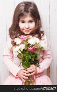 Little pretty girl in pink holds the bouquet of roses. Close up the flowers and face. Girl with roses