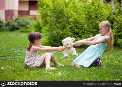 little pretty girls girlfriends sitting on the lawn and quarrel over toys