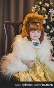 Little Princess in a fur coat around the Christmas tree.. Portrait of a child in a fur coat around the Christmas tree 4546.