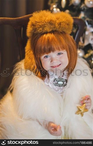 Little Princess in a fur coat around the Christmas tree.. Portrait of a child in a fur coat around the Christmas tree 4548.