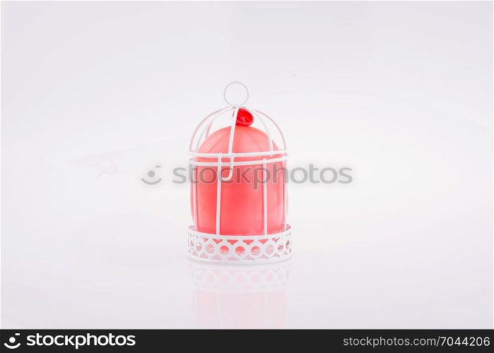 Little red balloon placed in a white color bird house with metal bars