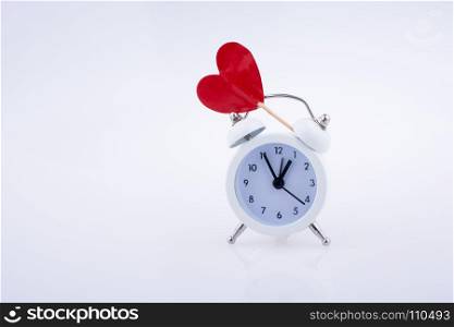 Little red color heart shape and white color alarm clock