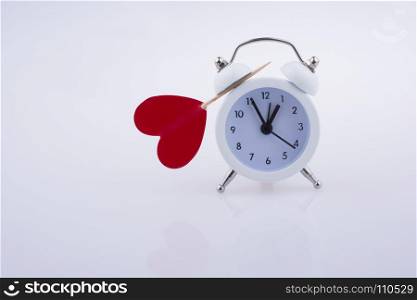 Little red color heart shape and white color alarm clock