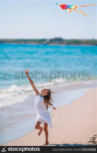 Little running girl with flying kite on the beach. Little girl flying a kite on beach at sunset