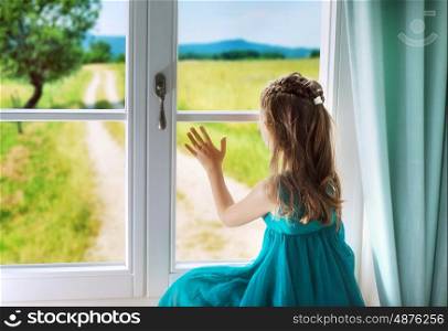 Little sad girl looking through window