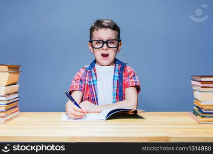 Little schoolboy learns homework at the desk in classroom. Pupil in glasses gets knowledge. Schoolboy learns homework, education concept