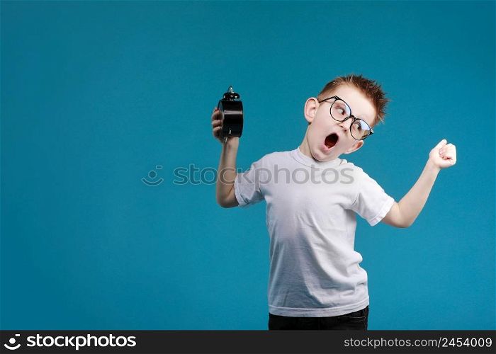 little schoolboy with ringing alarm clock is stretching and yawns, lazy going to school. blue background. Define your own rhythm of life. Happy hours concept. Schedule and timing.. little schoolboy with ringing alarm clock is stretching and yawns, lazy going to school. blue background. Define your own rhythm of life. Happy hours concept. Schedule and timing
