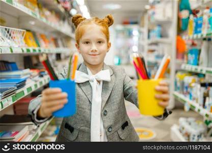 Little schoolgirl with colorful pencils, shopping in stationery store. Female child buying office supplies in shop, schoolchild in supermarket. Schoolgirl with colorful pencils, stationery store