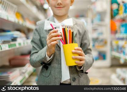 Little schoolgirl with colorful pencils, shopping in stationery store. Female child buying office supplies in shop, schoolchild in supermarket