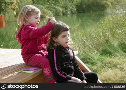 Little sister girls hairdresser on the river ourdoor park