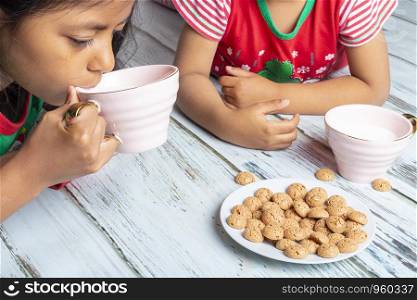 Little sisters eating cookies with milk on Christmas day