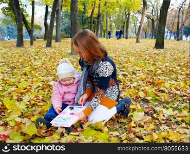 little sisters read the book in the autumn park. little girls sisters read the book in the autumn park
