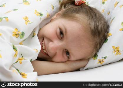 little smiling girl lying at the bed