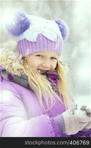 little smiling girl outdoors at the snowfall time