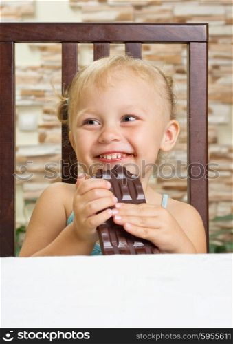 Little smiling girl with chocolate at light room