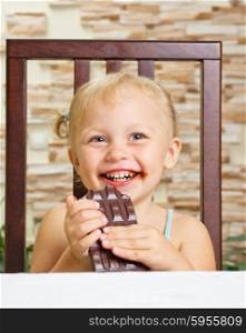 Little smiling girl with chocolate at the table