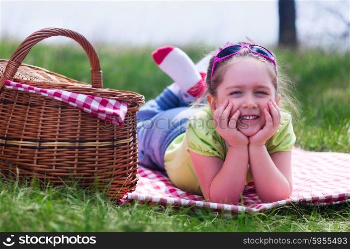 Little smiling girl with picnic basket at forest