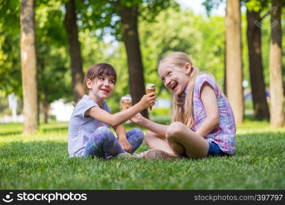 little smiling girls girlfriends sitting on the lawn and eating ice cream. children's holidays