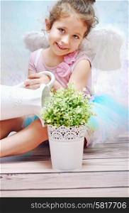 Little smiling kid watering plant