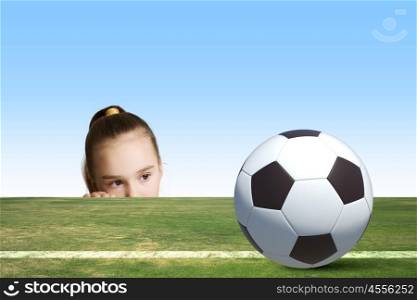 Little soccer player. Little cute girl looking at soccer ball