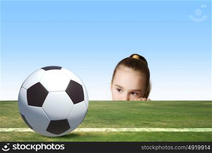 Little soccer player. Little cute girl looking at soccer ball