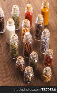 Little souvenir bottles with spices over wooden table