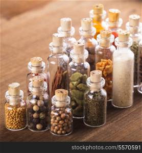 Little souvenir bottles with spices over wooden table
