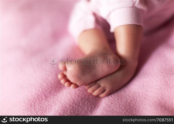 Little sweet legs of baby girl on pink background. Concept: kids, parenthood, family, baby shower, care. Copy space for text. Horizontal format. Selective focus. Close-up