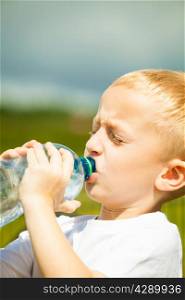 Little thirsty boy child drink water from plastic bottle, outdoor