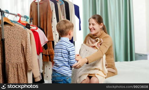 Little toddler boy helping his mother choosing clothes to wear in wardrobe at bedroom. Little toddler boy helping his mother choosing clothes to wear in wardrobe at bedroom.