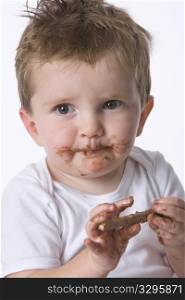 Little Toddler Boy Is Eating A Chocolate Snack