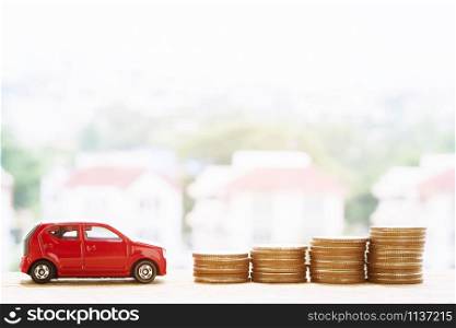 Little toy red car over a lot of money stacked coins. for bank loans costs finance. insurance, buying car finance concept. buy and pay by installments down payment a car.
