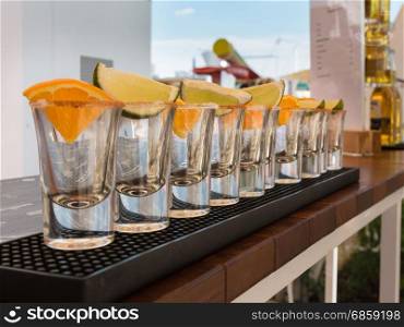 Little Transparent Glasses in Line with Orange and Lime Slices Ready to Tequila Shots