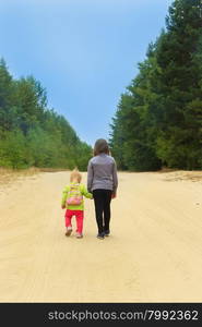 little travellers go on the forest road . little travellers sisters go on the forest road holding hands